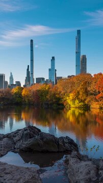 Early morning on Central Park Lake in Autumn colors with view of New York City Billionaire's Row. Timelapse cityscape of fall foliage and luxury apartment skyscrapers