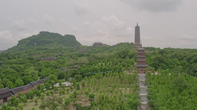 Aerial view of the serene Buddhist complex and pagoda surrounded by lush greenery and mountains, Gia Sinh, Ninh Binh, Vietnam.