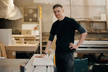 Man working on wood cut table with electric circular saw for chipboard for furniture production. Professional carpenter cutting wooden board at sawmill