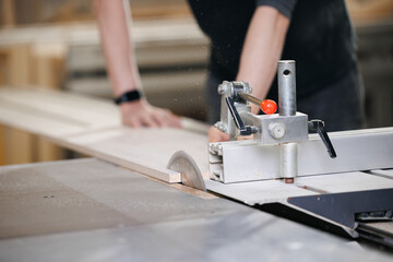 Closeup of wood cut table with electric circular saw for chipboard for furniture production. Professional carpenter cutting wooden board at sawmill
