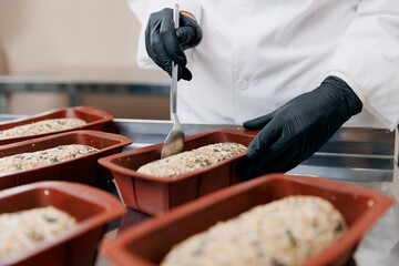 Baker prepares free gluten multigrain bread with seeds, shapes it for baking in oven. Bakery eco healthy food