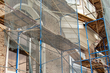 Scaffolding covered with protective net. Restoration of the facade of building