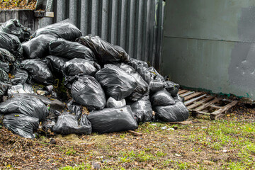 Garbage bags piled in pile. An overflowing dumpster. Space for text