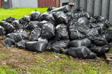 Black garbage bags with garbage. Garbage bags piled in pile