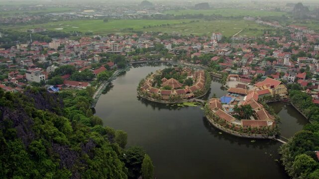 Aerial view of tam coc lake with hotel complex and rowboats surrounded by lush greenery, tam coc, Vietnam.