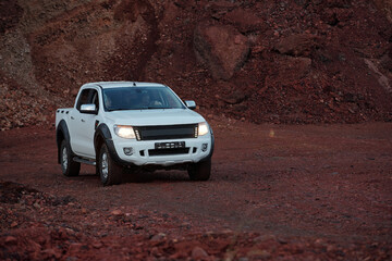 White pickup truck with driver and young female traveler inside moving along country road surrounded by crimson rocks or mountains