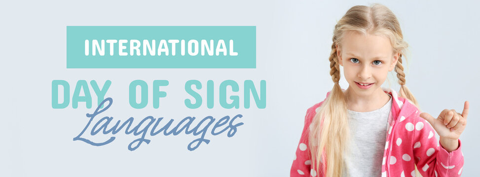 Little deaf mute girl using sign language on light background