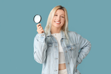 Young woman with magnifier on blue background