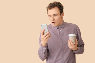 Shocked young man with smartphone and coffee on beige background