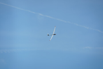 A glider plane soaring through the sky with clouds in the background, high above the Bavarian Alps.