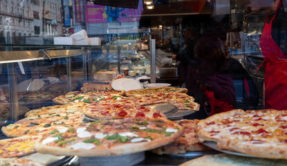 Pizza shop display. Assortment of italian pizzas closeup view. Street food in NYC