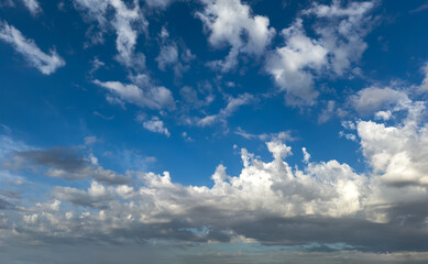 Fototapeta premium Fluffy cumulus clouds on blue sky background. Cloudscape white and grey color