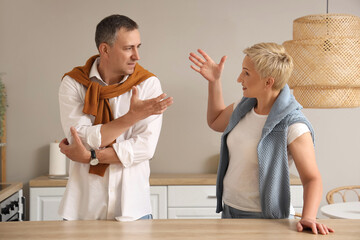 Mature woman quarreling with her husband in kitchen