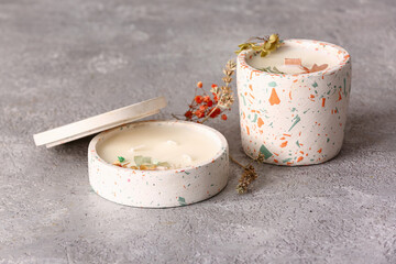 Holders with candles and flowers on grey background