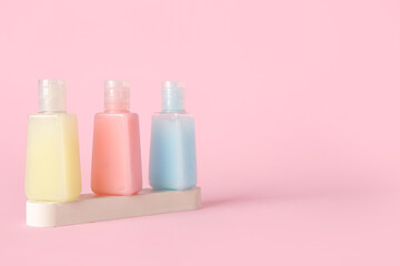 Plaster podium with bottles of different cosmetic products on pink background