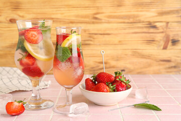 Glasses of fresh lemonade with strawberry and lemon on pink tile table