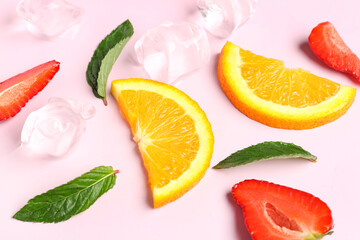 Orange slices with strawberries, ice cubes and mint on pink background