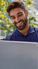 Positive male freelancer working on laptop standing on skyscrapers background. Distance work concept