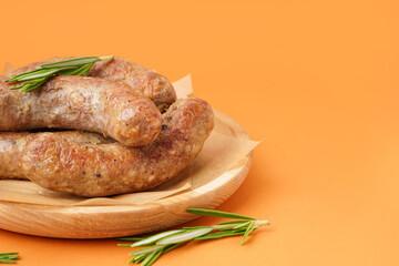 Plate with tasty homemade sausages on orange background