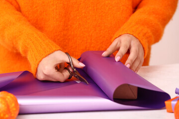 Woman wrapping gift box for Halloween at white table