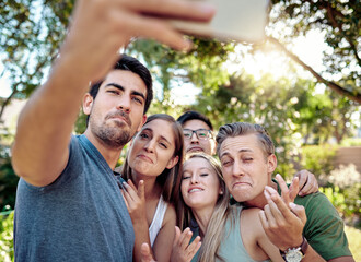 Comic, funny face and selfie with group of friends outdoor in nature together for bonding or profile picture. Comedy, humor or joking with smile of men and women in park for photograph of break