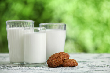 Glasses of fresh milk and sweet cookies on grunge table outdoors