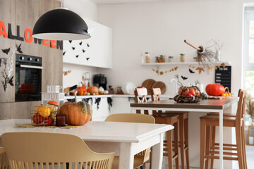 Interior of light kitchen decorated for Halloween with counters and dining tables