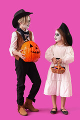 Little children dressed for Halloween with candies and pumpkin on purple background