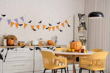 Interior of light kitchen decorated for Halloween with counters and dining table