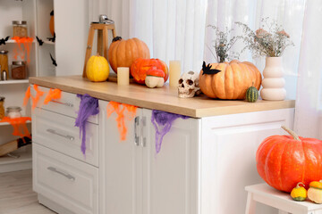 Interior of light kitchen decorated for Halloween with counters and pumpkins