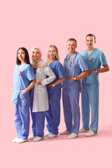 Professional team of doctors with red ribbons on pink background. World AIDS Day concept