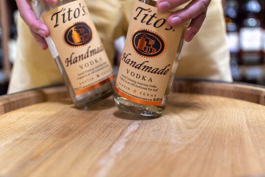Bottles of USA Texas Austin Tito's Handmade vodka close-up in man hands on oak cask. Ukraine, Zhytomyr, August, 21, 2024