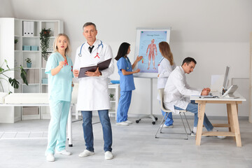 Obraz premium Team of doctors with red ribbons working in clinic. World AIDS Day concept