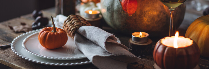 Beautiful seasonal decorated Thanksgiving table for cozy family dinner or fall luxury countryside wedding. Elegant beautiful setting for holiday event, party, reception. Wineglasses and fancy dishes.