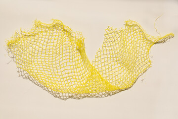 yellow plastic produce mesh, fruit net, netting on white © Nicole Kandi