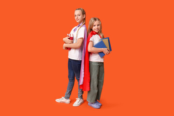 Cute teenage girls dressed as superhero with books on orange background. Library Lovers Day