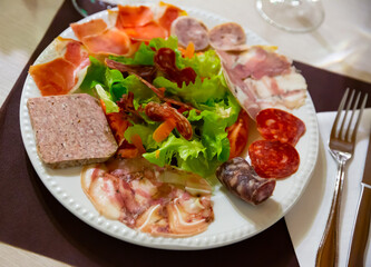 Appetizing Catalan salad with fresh lettuce, tomatoes, onion and olives with sliced traditional sausages and cured meat.