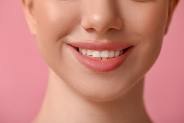 Smiling young woman with beautiful lips on pink background, closeup