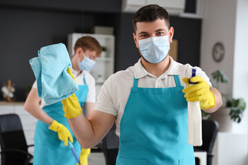 Male worker of cleaning service with disinfectant and rag in office