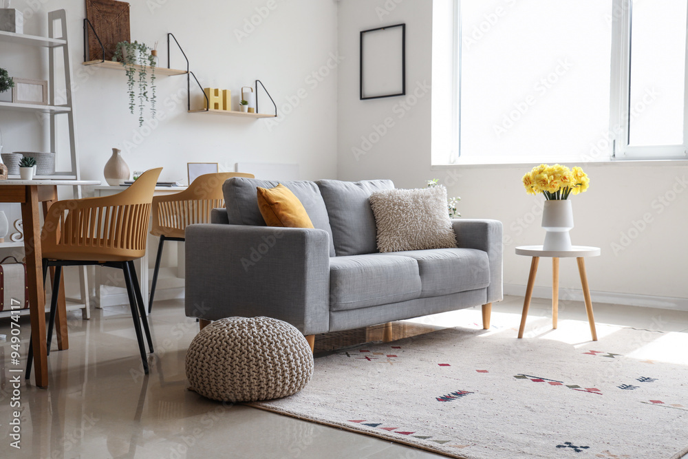 Sticker comfortable sofa and vase with daffodil flowers on coffee table in living room