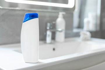 Bottle of shampoo with mockup for your brand design on washbasin on bathroom counter, free space, selective focus