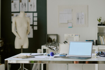 Metal desk with digital devices and sketches in fashionable atelier