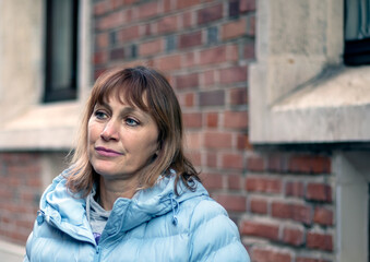 Portrait of a thoughtful beautiful middle-aged European woman against a brick wall