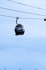 gondolas of the Gaia cable car passing just above typical houses in the Vila Nova de Gaia neighborhood, under a cloudy sky in Porto. Portugal