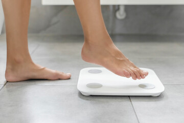 Lose weight concept. Woman standing on electronic scales for weight control, using modern...