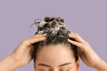 Fototapeta premium Beautiful young woman washing her hair with shampoo on purple background, closeup