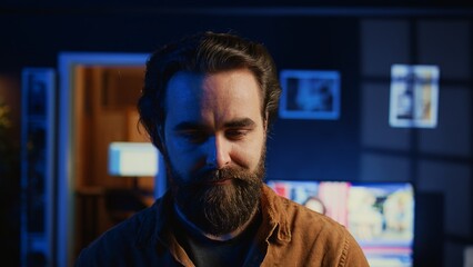 Portrait of happy man doing IT support job from apartment, standing in personal office with laptop in hand, coding. Joyful developer writing lines of code on notebook, camera B close up shot