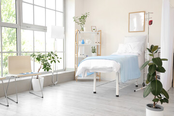 Interior of hospital ward with bed, shelf unit and plants