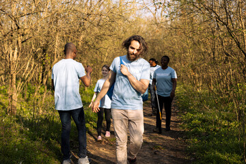 African american team leader congratulating his colleagues with a high five, praising each other after finishing litter cleanup in the woods. Group of activists feeling happy with their perseverance.