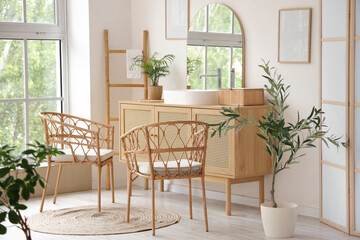 Wicker chairs, ladder and chest of drawers in interior of modern bathroom